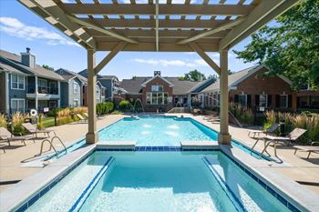 A large swimming pool under a wooden pergola.